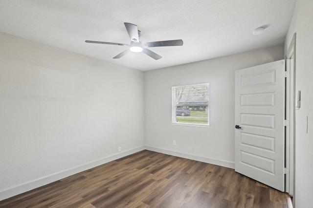 spare room with dark wood finished floors, a ceiling fan, and baseboards