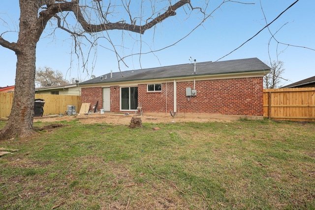 back of property featuring fence private yard, brick siding, and a yard