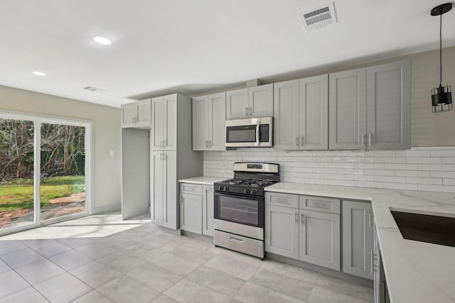 kitchen with light stone counters, stainless steel appliances, gray cabinets, visible vents, and backsplash