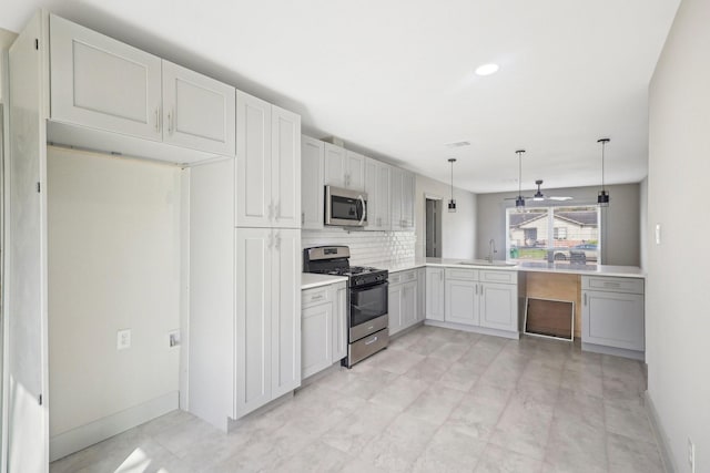 kitchen with pendant lighting, tasteful backsplash, light countertops, appliances with stainless steel finishes, and a sink