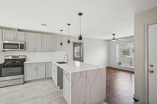 kitchen featuring stainless steel appliances, a peninsula, a sink, visible vents, and decorative backsplash