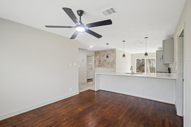 interior space featuring visible vents, a sink, baseboards, and wood finished floors