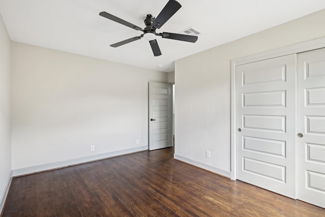 unfurnished bedroom with baseboards, visible vents, a ceiling fan, dark wood-style floors, and a closet