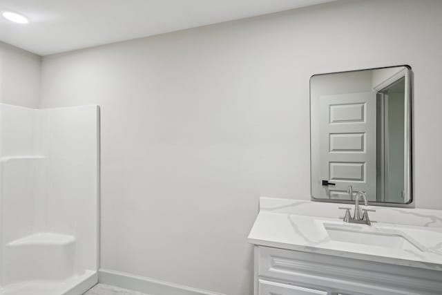 bathroom featuring baseboards, walk in shower, and vanity