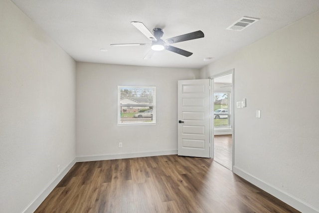 unfurnished room with baseboards, visible vents, a wealth of natural light, and wood finished floors