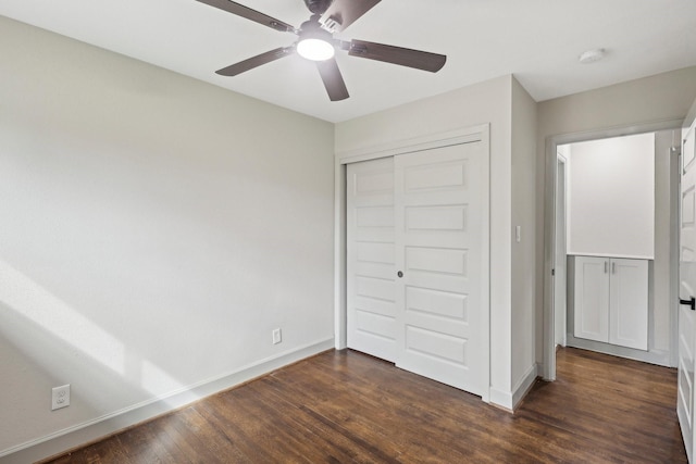 unfurnished bedroom featuring dark wood-style floors, ceiling fan, a closet, and baseboards