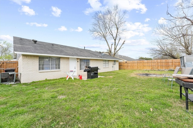 back of house featuring brick siding, a lawn, and a fenced backyard