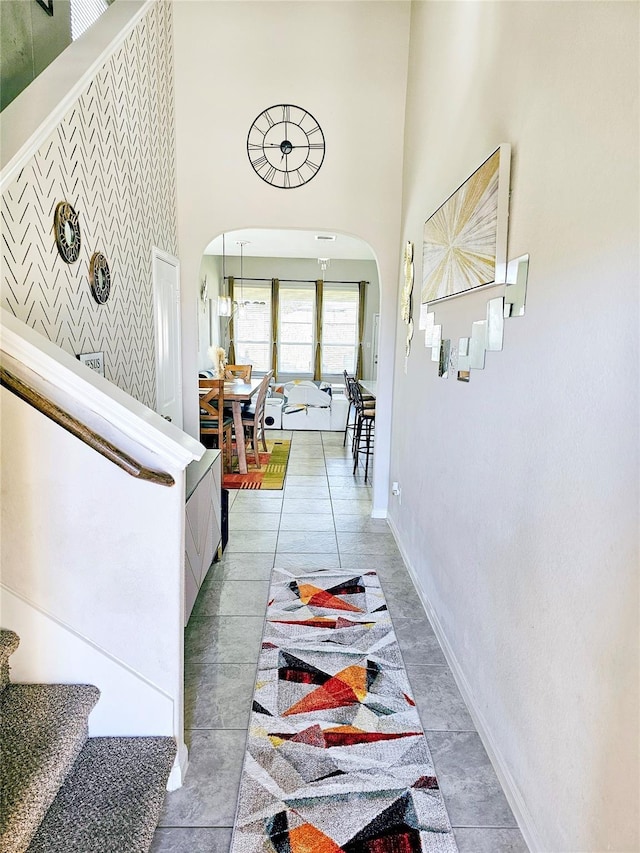 hallway with baseboards, a high ceiling, and arched walkways