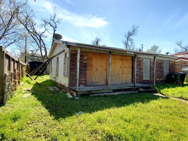 rear view of house with a yard, brick siding, and fence