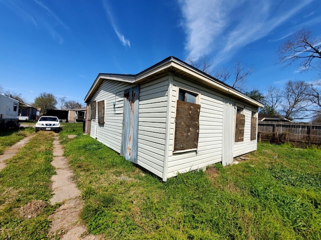 view of side of home with a yard and fence