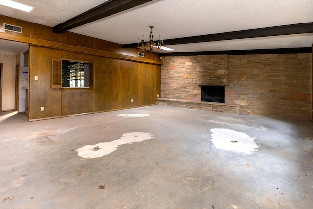 unfurnished living room with wooden walls, visible vents, unfinished concrete floors, beamed ceiling, and a fireplace