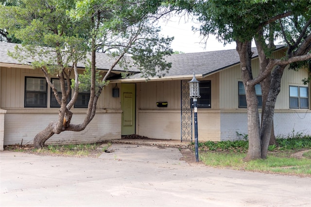 view of front of property featuring roof with shingles, a carport, and brick siding