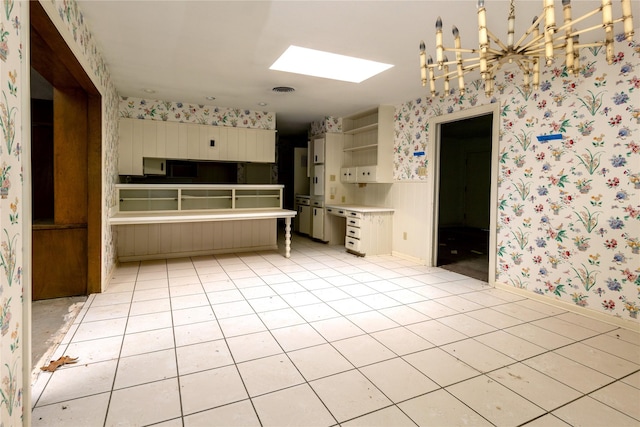 kitchen with a skylight, light tile patterned floors, open shelves, wainscoting, and wallpapered walls