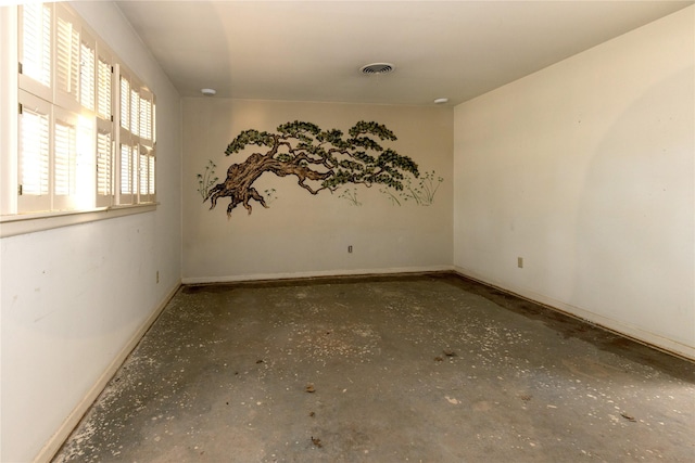 spare room featuring baseboards, concrete floors, and visible vents