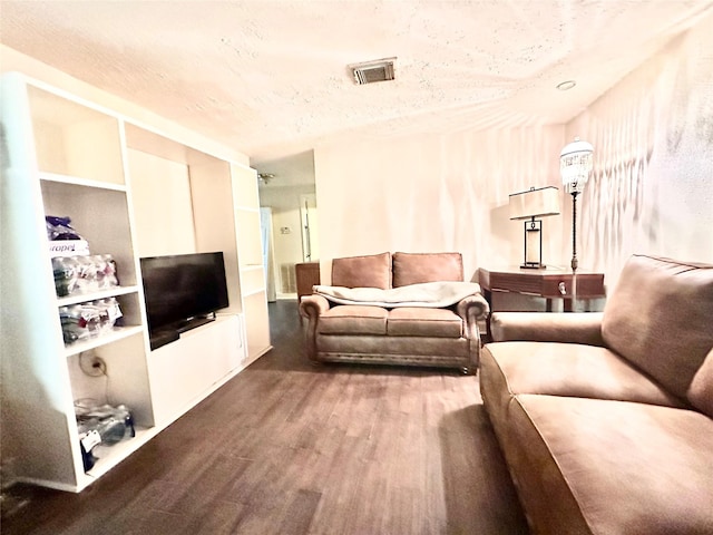 living room with visible vents, a textured ceiling, and wood finished floors