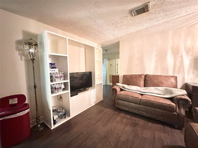 living area featuring dark wood-style flooring, visible vents, and a textured ceiling