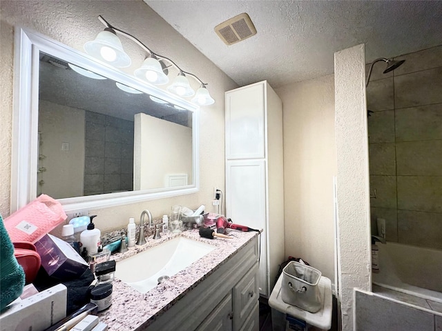 full bath with visible vents, vanity, a textured ceiling, and bathing tub / shower combination