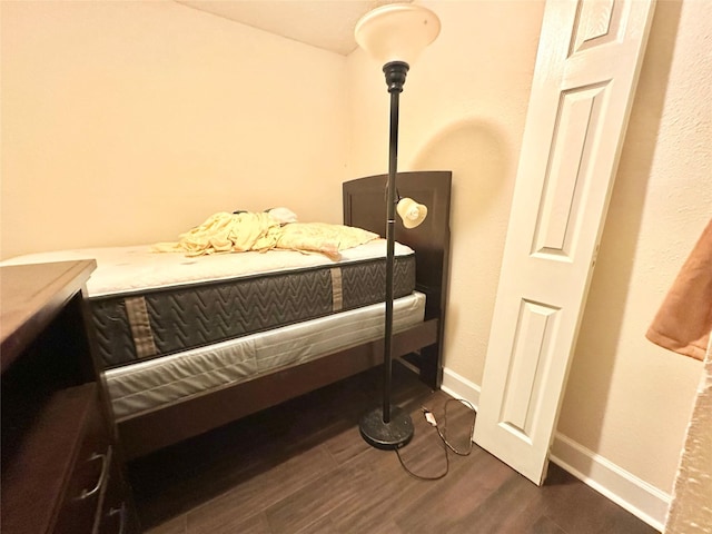 bedroom with dark wood-type flooring and baseboards