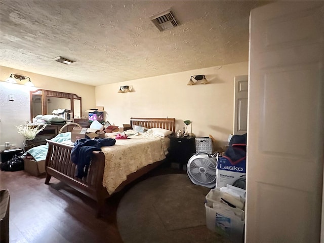 bedroom with a textured ceiling, wood finished floors, and visible vents