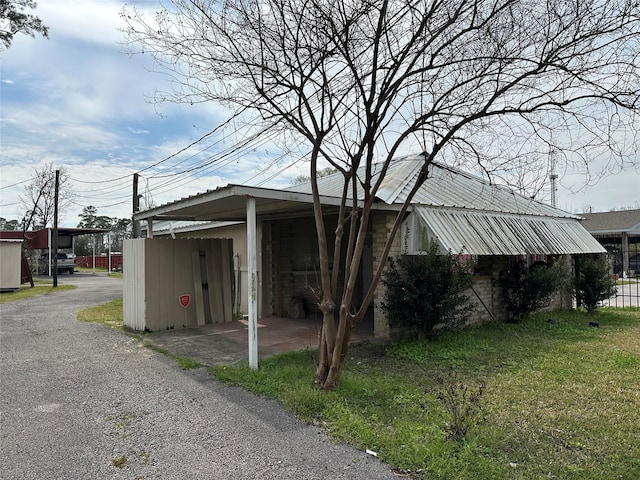 view of home's exterior with aphalt driveway, a yard, and metal roof