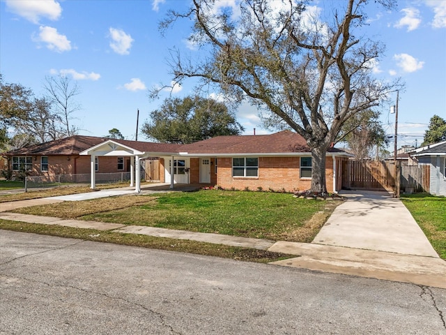 single story home featuring a front lawn, a carport, fence, concrete driveway, and brick siding