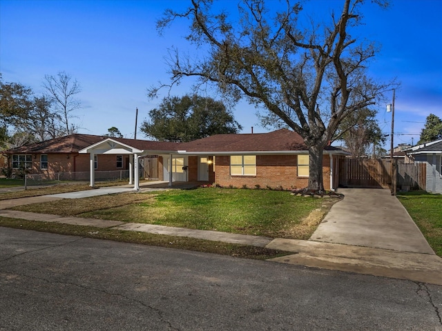 ranch-style home with fence, a carport, concrete driveway, a front lawn, and brick siding