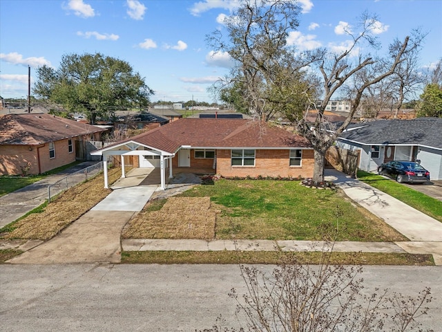 view of front facade with brick siding, an attached carport, fence, a front yard, and driveway