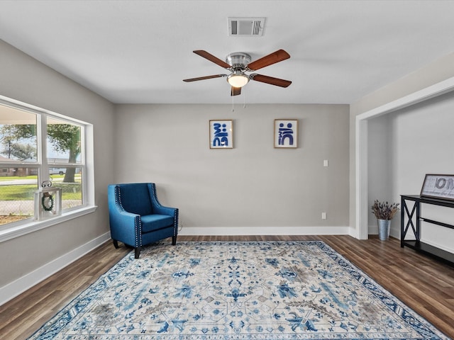 living area with visible vents, ceiling fan, baseboards, and wood finished floors