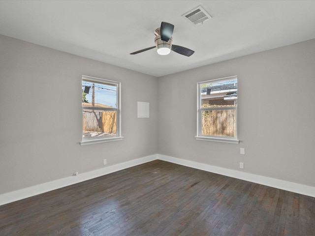 spare room with a ceiling fan, dark wood-style floors, visible vents, and baseboards