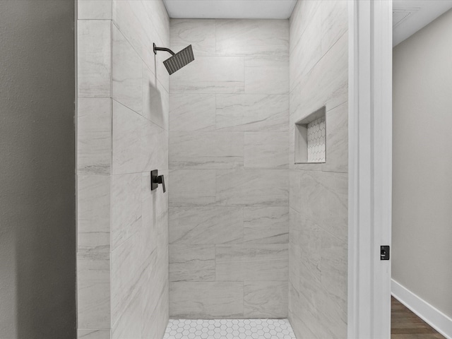 bathroom featuring baseboards and a tile shower