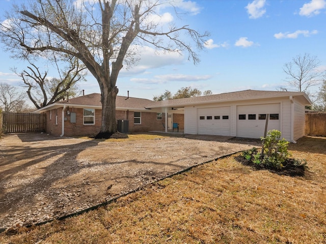 single story home featuring brick siding, an attached garage, fence, central AC, and driveway