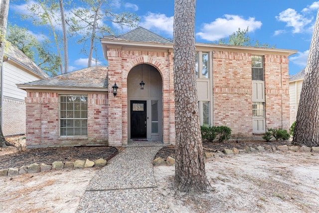 view of front of home with brick siding and a shingled roof