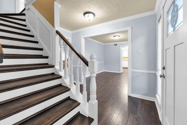 foyer featuring dark wood-style floors, ornamental molding, a textured ceiling, and baseboards