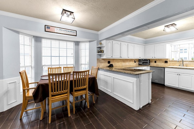 kitchen featuring white cabinets, dishwasher, dark wood-style flooring, a peninsula, and a sink