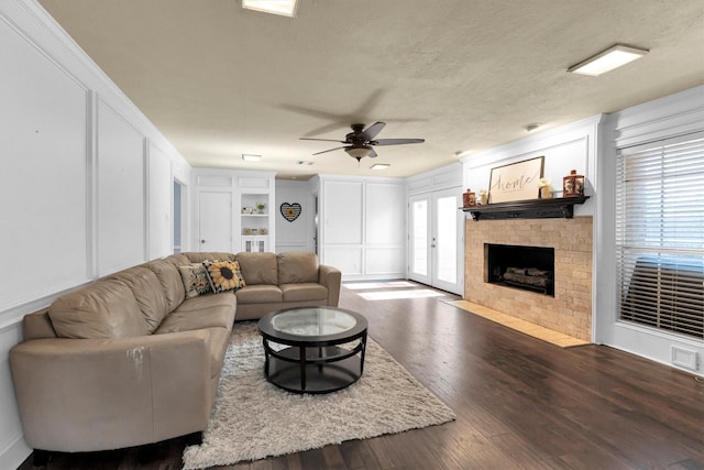 living area featuring visible vents, dark wood-style floors, a fireplace with flush hearth, a textured ceiling, and a decorative wall