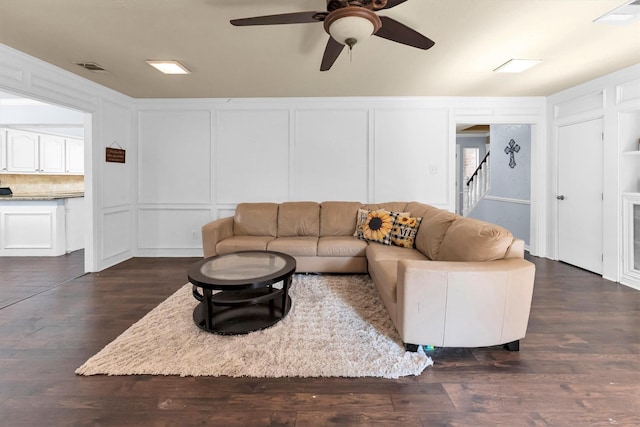 living area with stairway, visible vents, a decorative wall, and dark wood finished floors