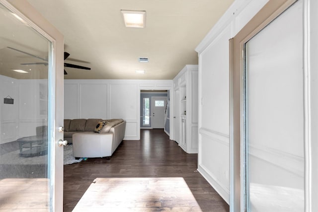 hall with dark wood-style floors, visible vents, and a decorative wall