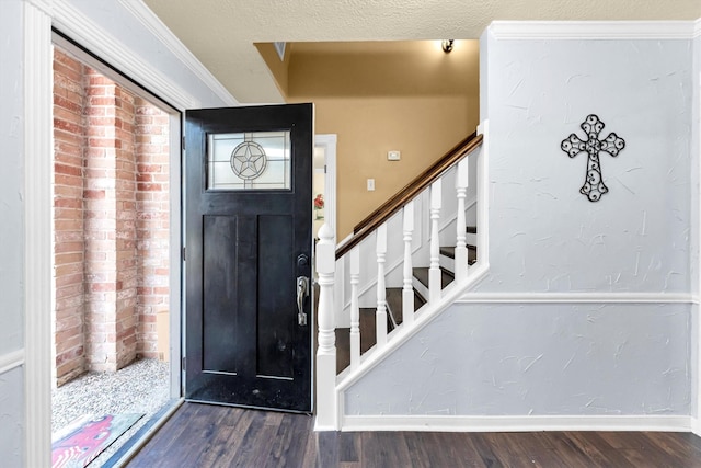 foyer with baseboards, a textured wall, stairway, wood finished floors, and a textured ceiling