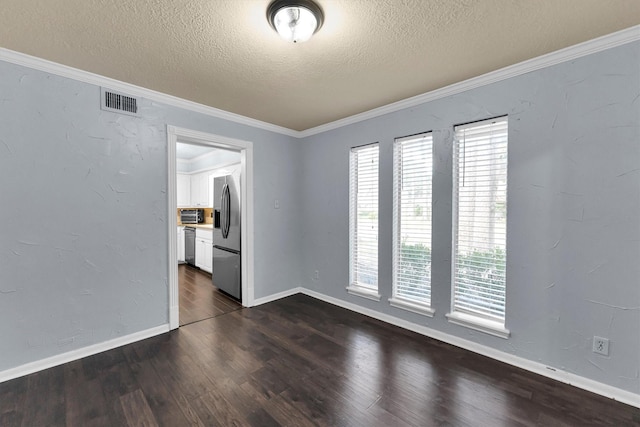 empty room with dark wood-style flooring, visible vents, ornamental molding, a textured ceiling, and baseboards