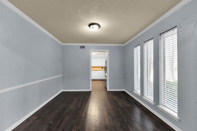 unfurnished room with dark wood-style floors, crown molding, visible vents, a textured ceiling, and baseboards