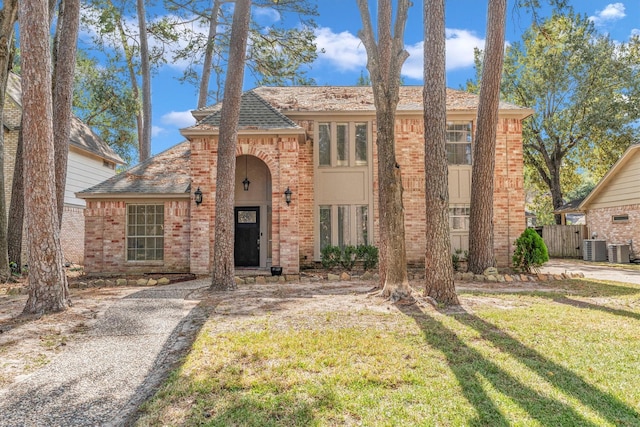 view of front of home with brick siding, a front lawn, cooling unit, and fence