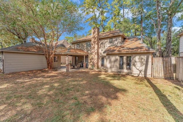 back of property with a patio, fence, french doors, a lawn, and a chimney