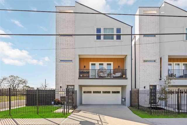 view of front facade featuring driveway, a fenced front yard, an attached garage, and stucco siding