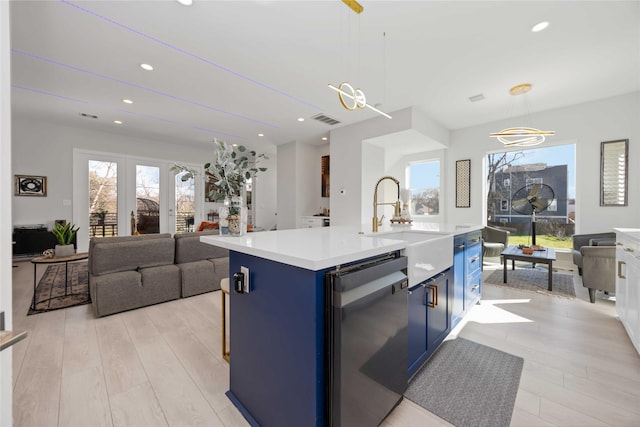 kitchen featuring light countertops, visible vents, a sink, blue cabinets, and dishwasher