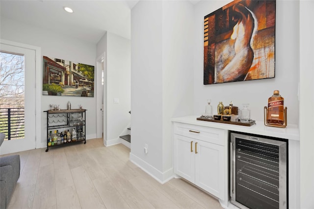 bar with light wood-type flooring, wine cooler, stairs, a bar, and recessed lighting