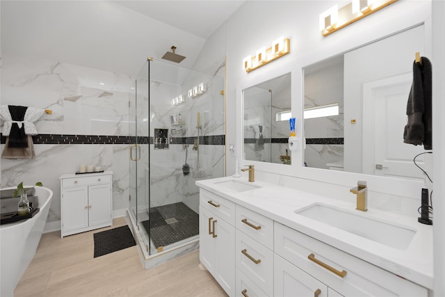 full bathroom with double vanity, a freestanding tub, a marble finish shower, and a sink