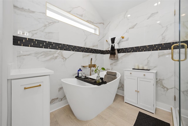 bathroom featuring vaulted ceiling, a freestanding tub, and a marble finish shower