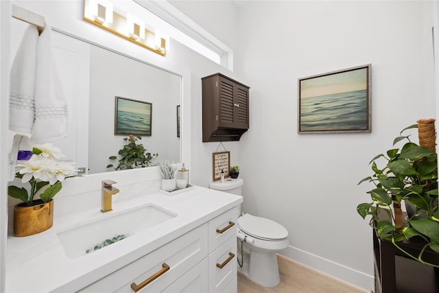 half bath featuring toilet, vanity, and baseboards