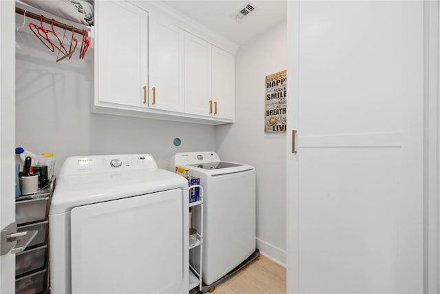 laundry room featuring washer and clothes dryer, visible vents, cabinet space, light wood-type flooring, and baseboards