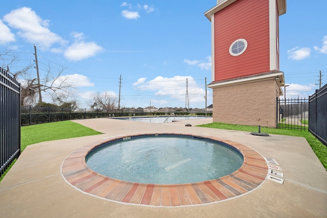 view of pool with a community hot tub, fence, and a lawn